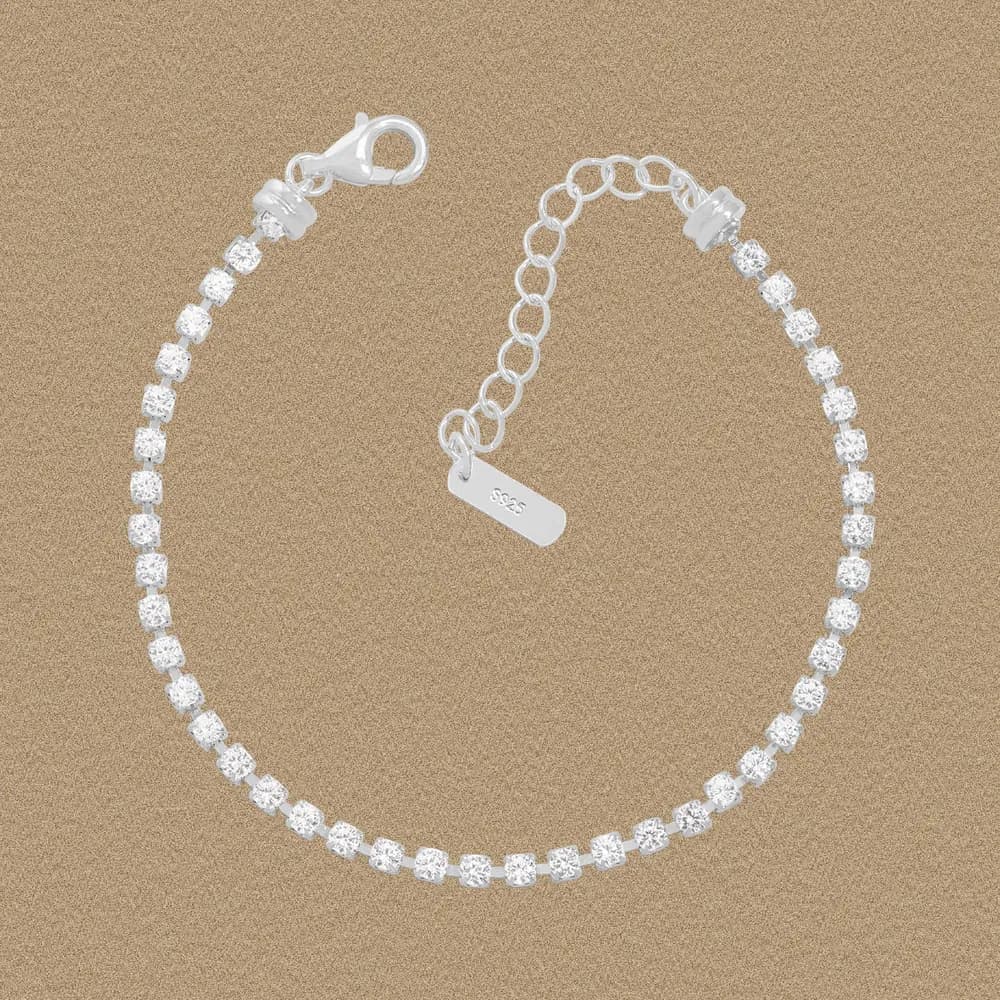 Polished sterling silver tennis bracelet with evenly spaced cubic stones and an adjustable extender on a neutral background.