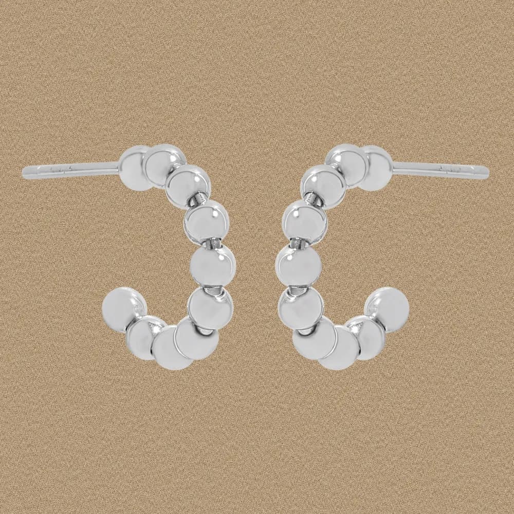 Polished sterling silver circle bead hoops with stacked discs on a beige background.