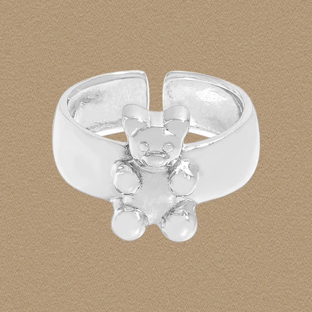 Polished sterling silver ring with a raised teddy bear charm on a wide band.