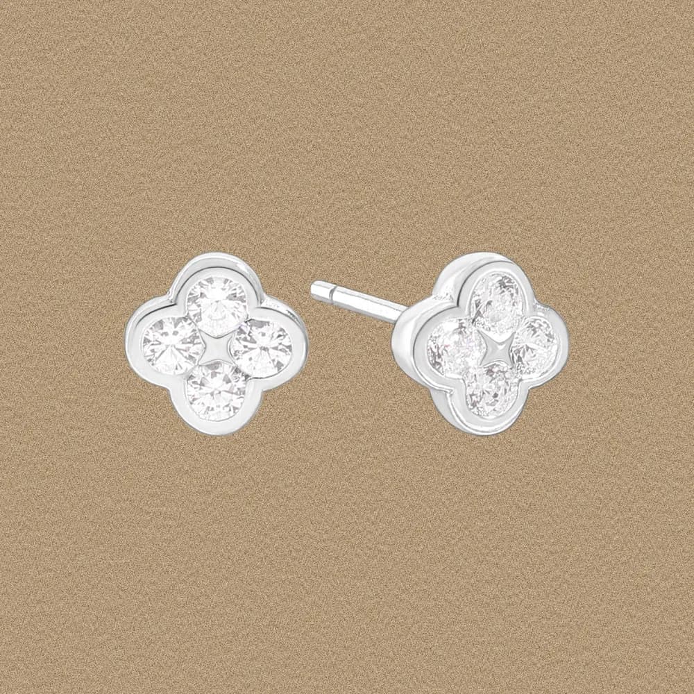 Polished sterling silver four-leaf clover stud earrings with four small clear stones on a neutral background.
