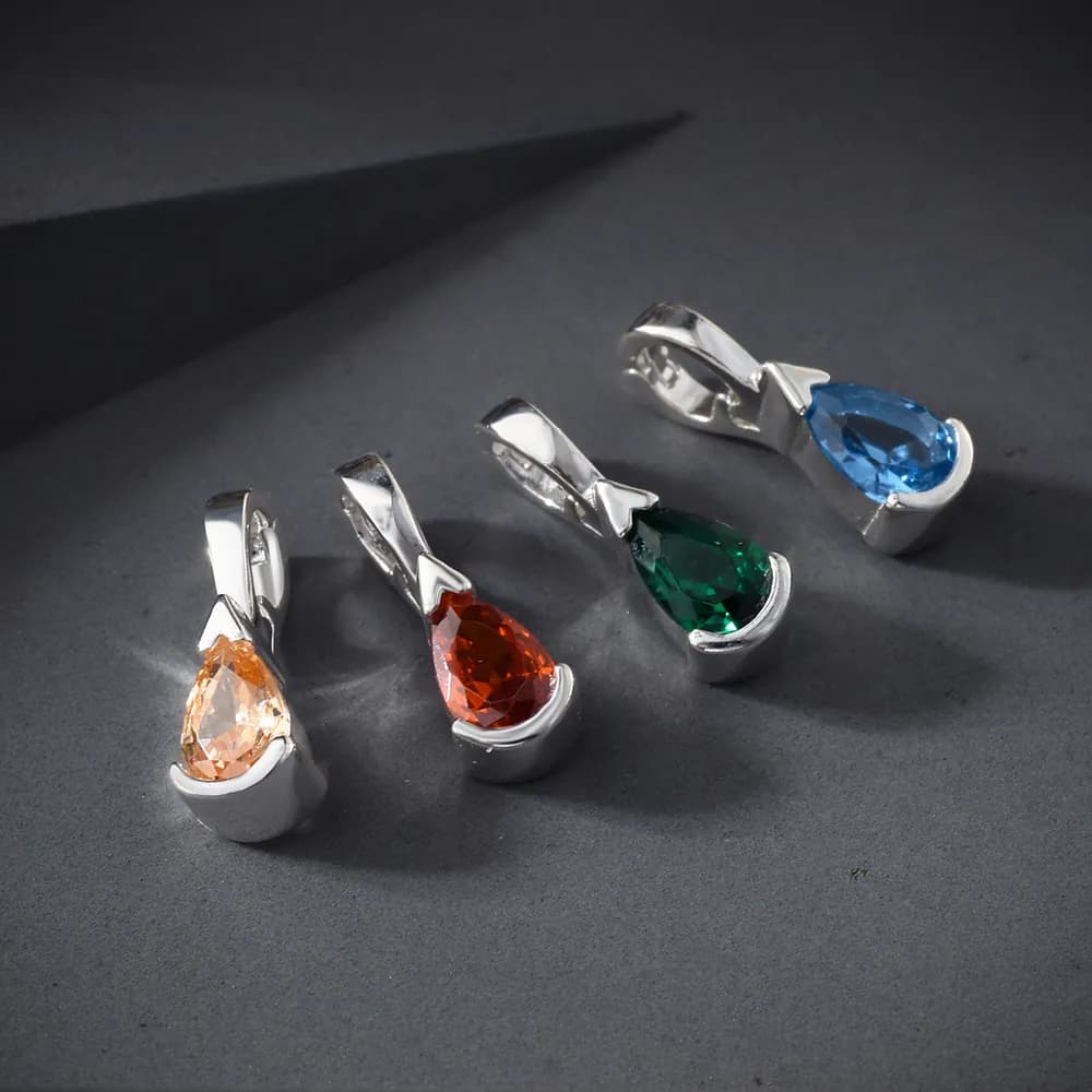 Five sterling silver teardrop pendants with colorful faceted crystals on a dark surface