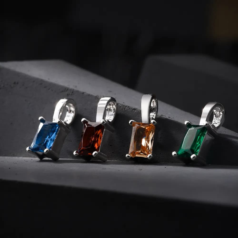 Four emerald-cut stones in blue, red, amber, and green suspended on a silver necklace with four-prong settings.