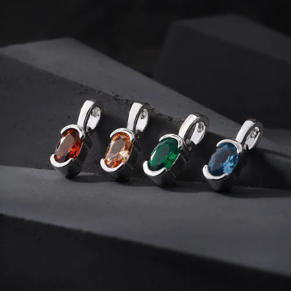 Four oval gemstone pendants in silver bezels arranged on a dark surface.