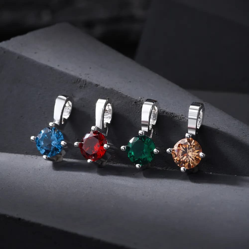 Four sterling silver gemstone pendants in blue, red, green, and peach with curved bails visible on a dark background.