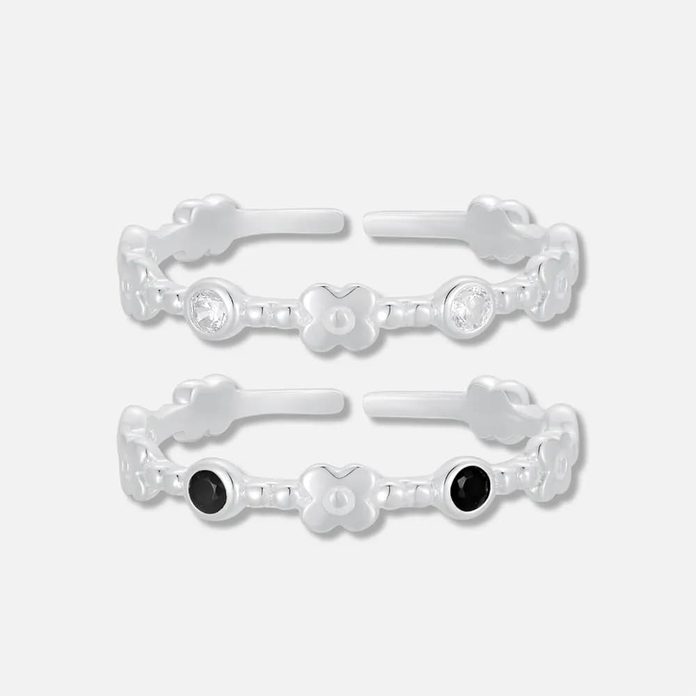 Two flower-link sterling silver rings with clear and black bezel stones shown side by side.