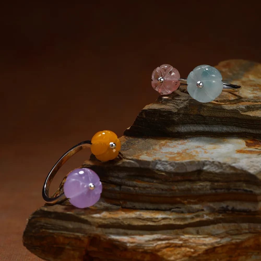 Open sterling silver ring with a colored enamel bead on the end, shown on a textured rock backdrop.
