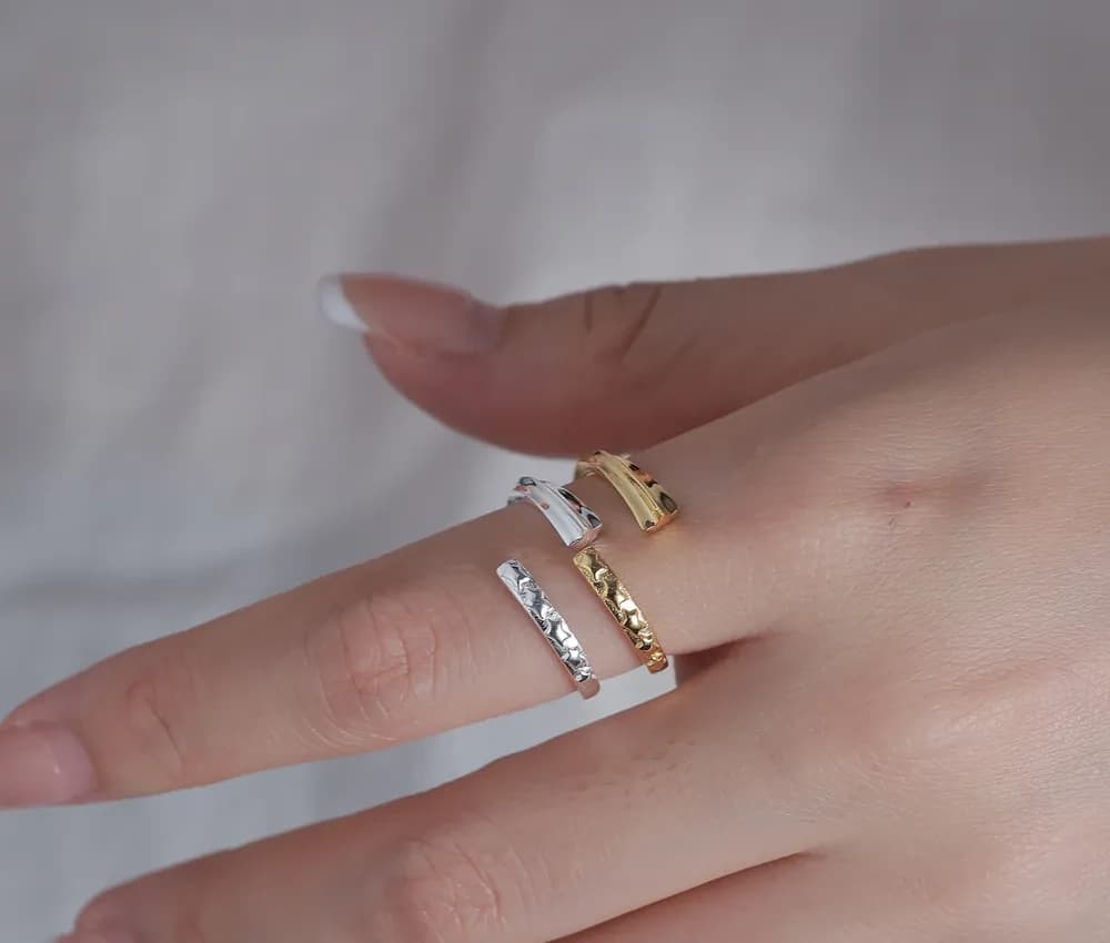 Three slender hammered rings in silver and gold tones stacked on a finger