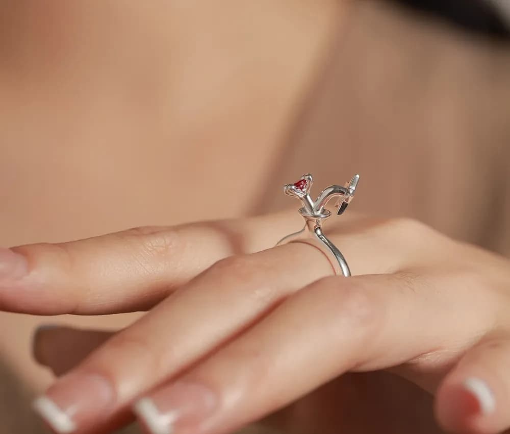 Close-up of a sterling silver Heart Gem Ring on a finger with a small red heart gemstone