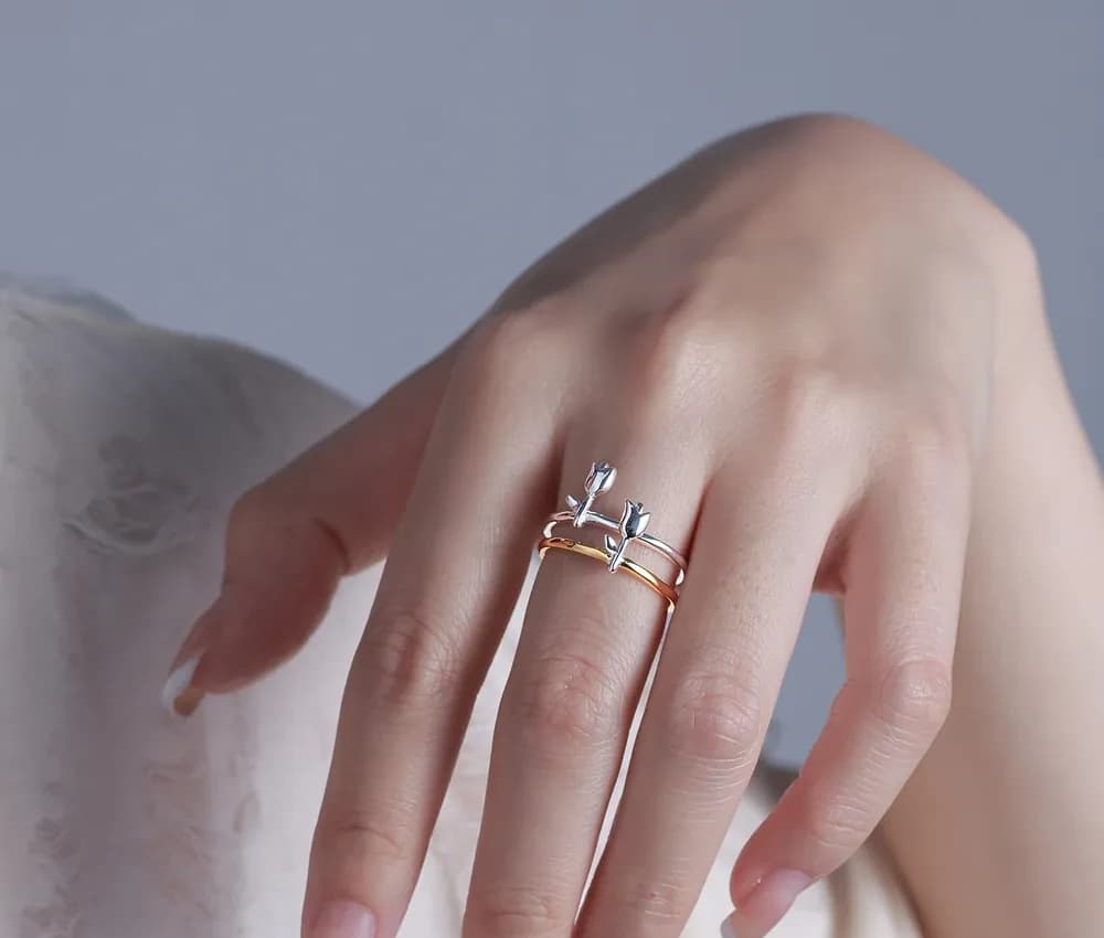 A two-tone, stacked ring on a finger, featuring a silver top band with bar accents above a warm-toned base band.