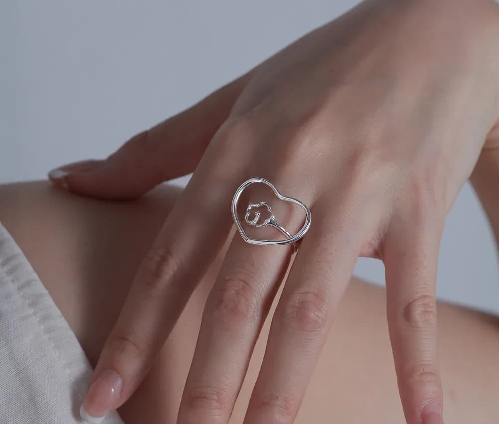 Polished sterling silver open-heart ring worn on a finger with a small inner heart detail