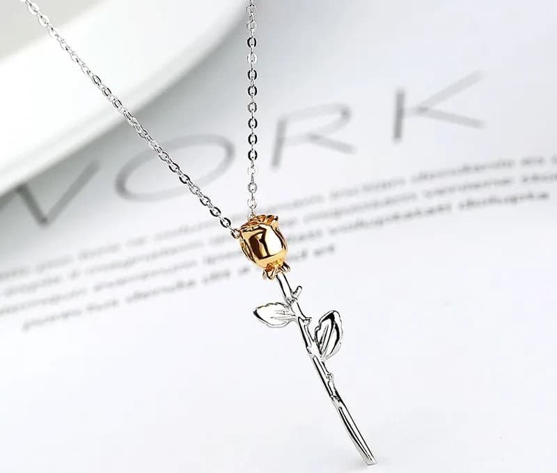 Vertical pendant with a silver stem and leaves, topped by a gold rose bud on a thin chain.