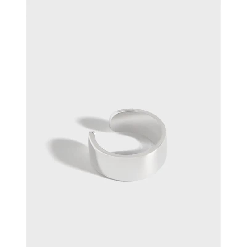 Polished curved open cuff earring in sterling silver on a light background.