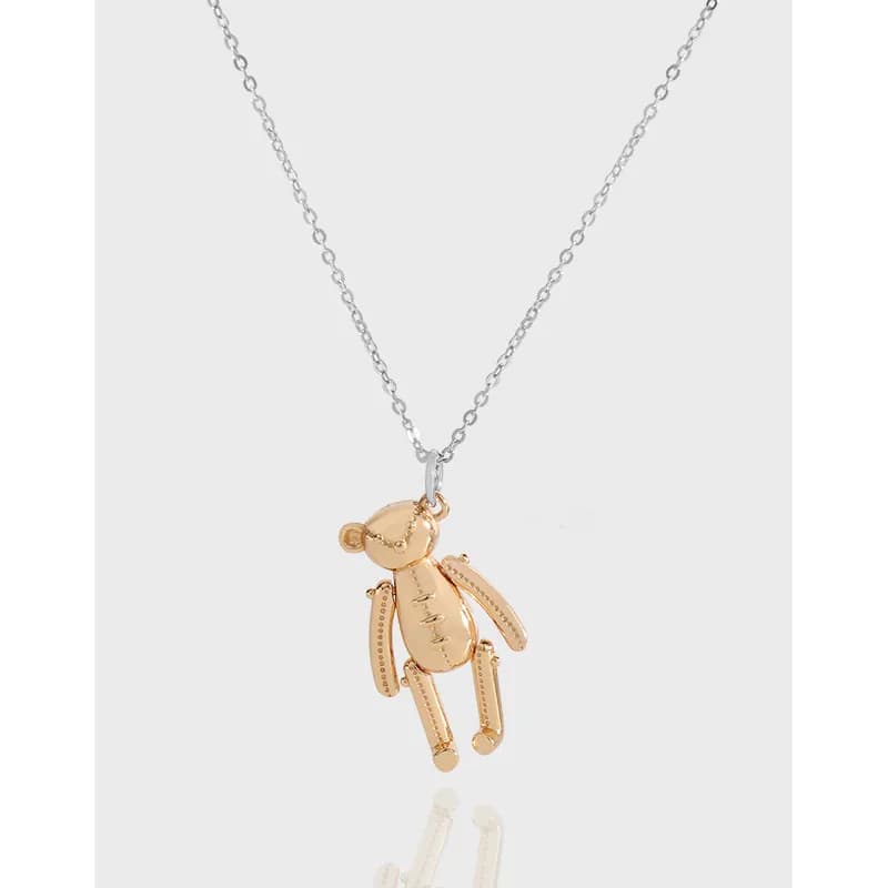 Polished silver chain with a small gold-tone teddy bear pendant hanging from a simple bail.