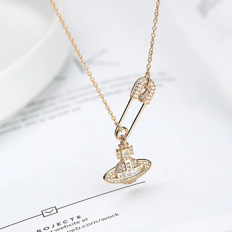 Polished sterling-silver necklace with a pavé crystal safety-pin pendant and a crystal orb charm on a delicate chain.