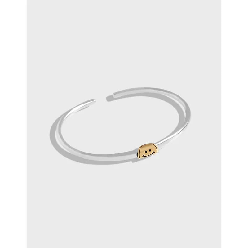 Polished sterling silver open cuff with a small gold smile bead on the front.