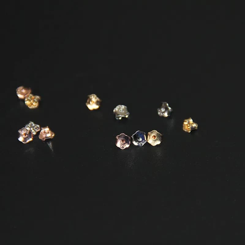 Close-up of small flower-shaped sterling silver stud earrings with polished petals.