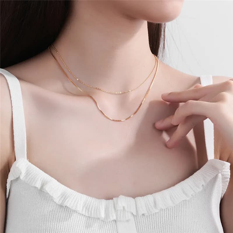 Close-up of a model wearing a two-layer polished silver necklace at the base of the neck.