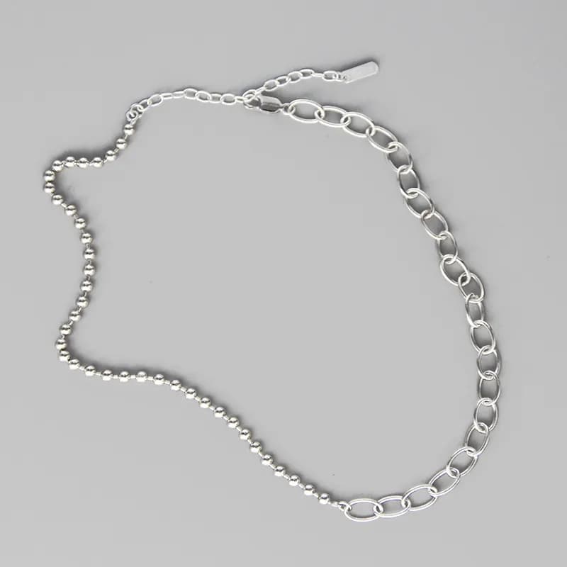 Sterling silver necklace with beaded ball chain on one side and oval-link cable chain on the other, laid flat.