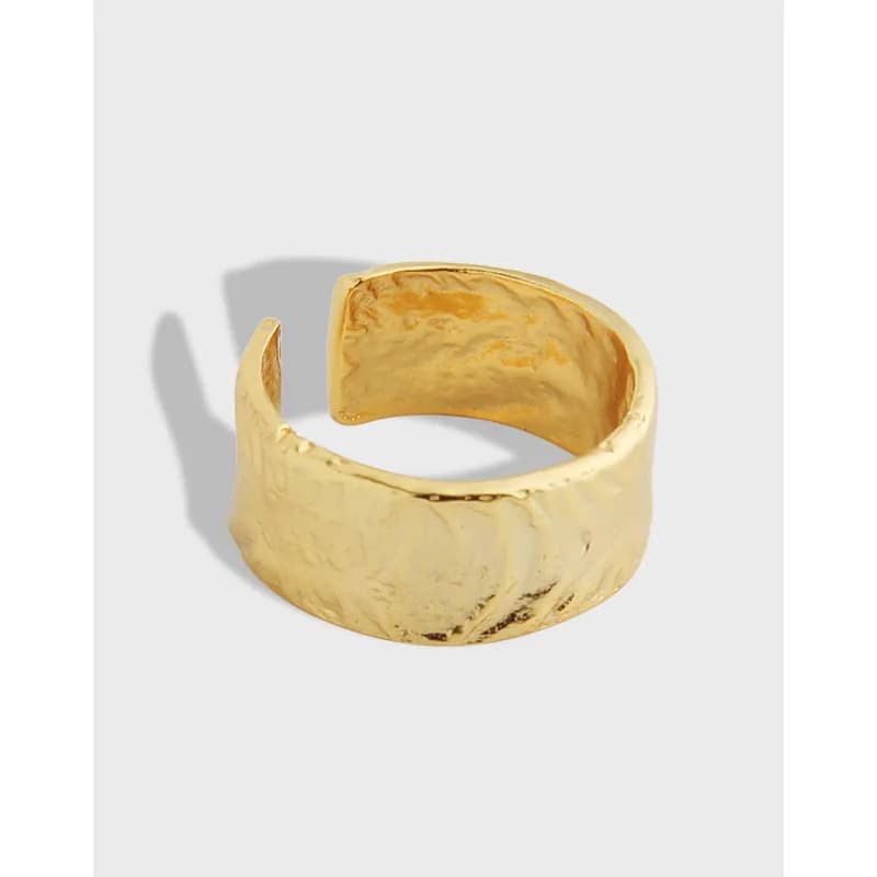 Polished hammered wide ring in sterling silver with an open gap and textured surface.