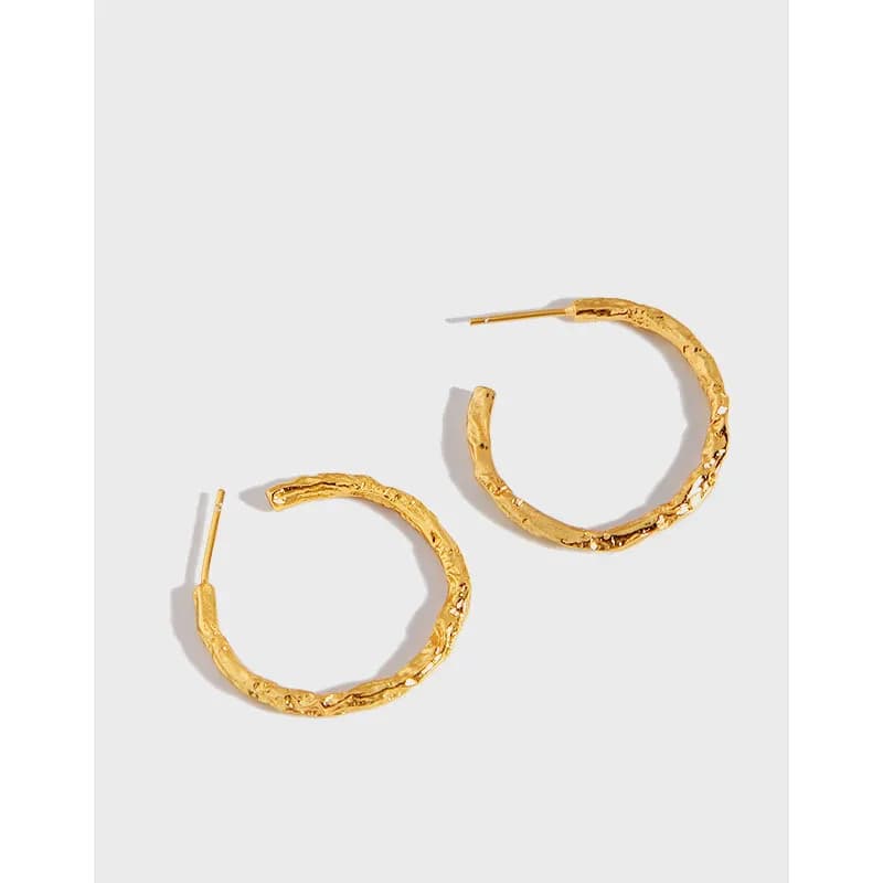 Polished hammered sterling silver hoop earrings with a textured surface and post backs.