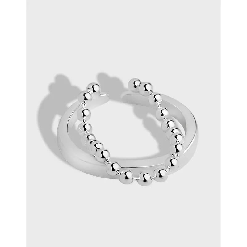 Two sterling silver rings, one smooth band and one beaded ball ring, resting together