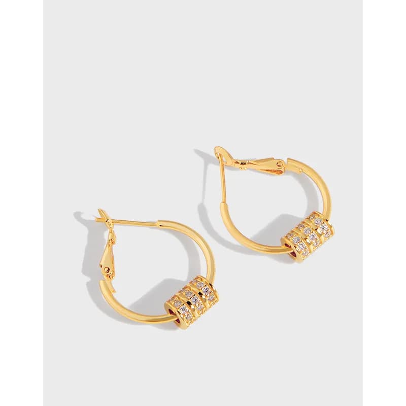 Close-up of polished sterling silver hoop earrings with a pavé cylinder detail at the bottom.
