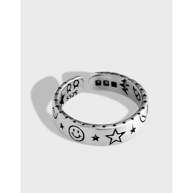 Polished sterling silver ring with smiley face, stars, and moon engravings around the band.