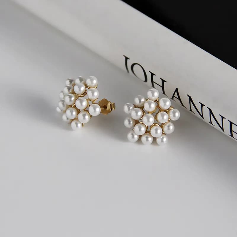 Close-up of two pearl cluster stud earrings on a white surface