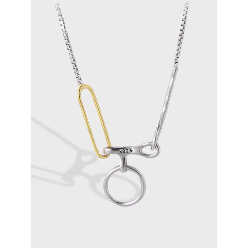Close-up of a two-tone safety pin inspired pendant on a polished silver chain