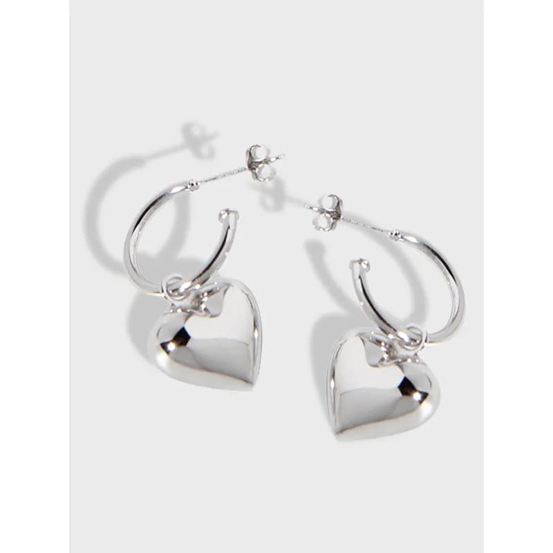 Polished sterling silver hoop earrings with dangling heart charms.