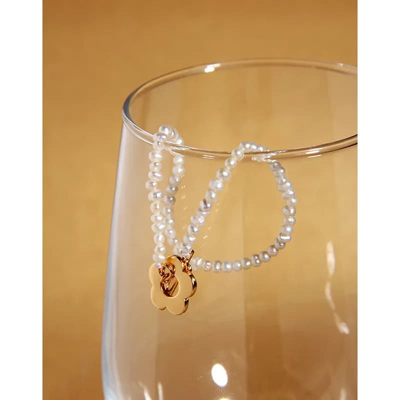 Polished sterling silver bracelet with two strands of small white pearls and a gold flower charm.