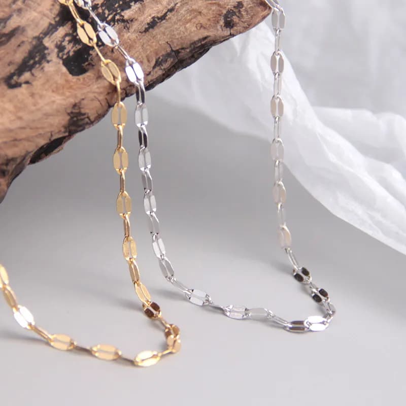 Delicate silver oval-link necklace with gold-tone variation resting on a light surface.