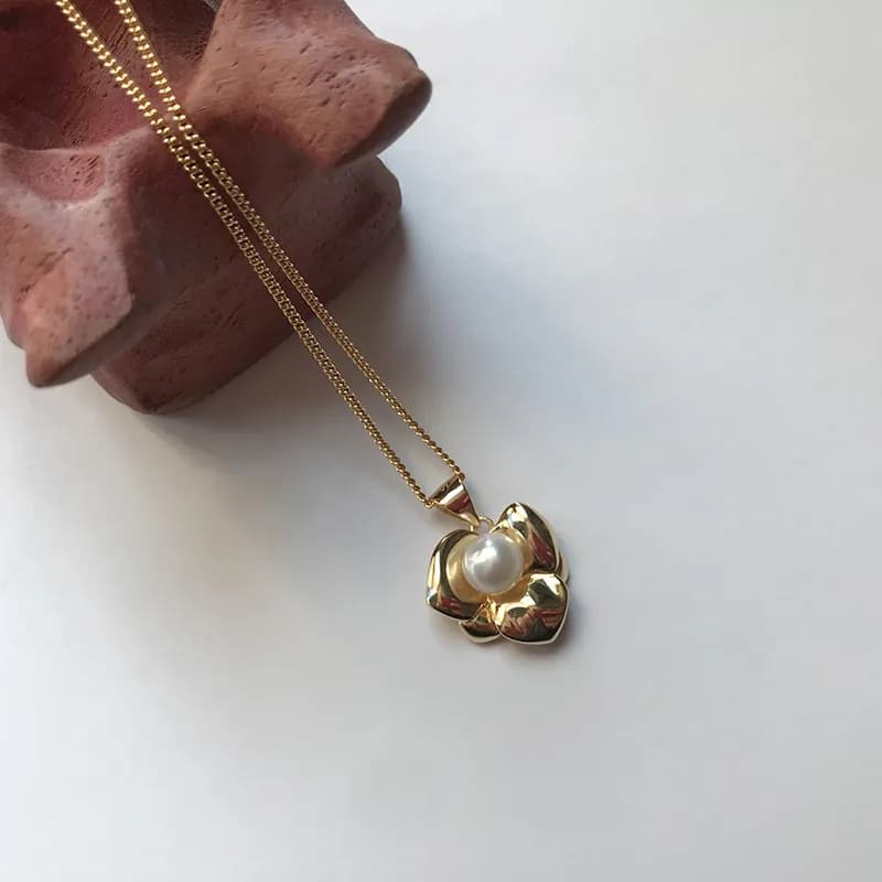 Polished silver flower pendant necklace with a central pearl on a slender chain