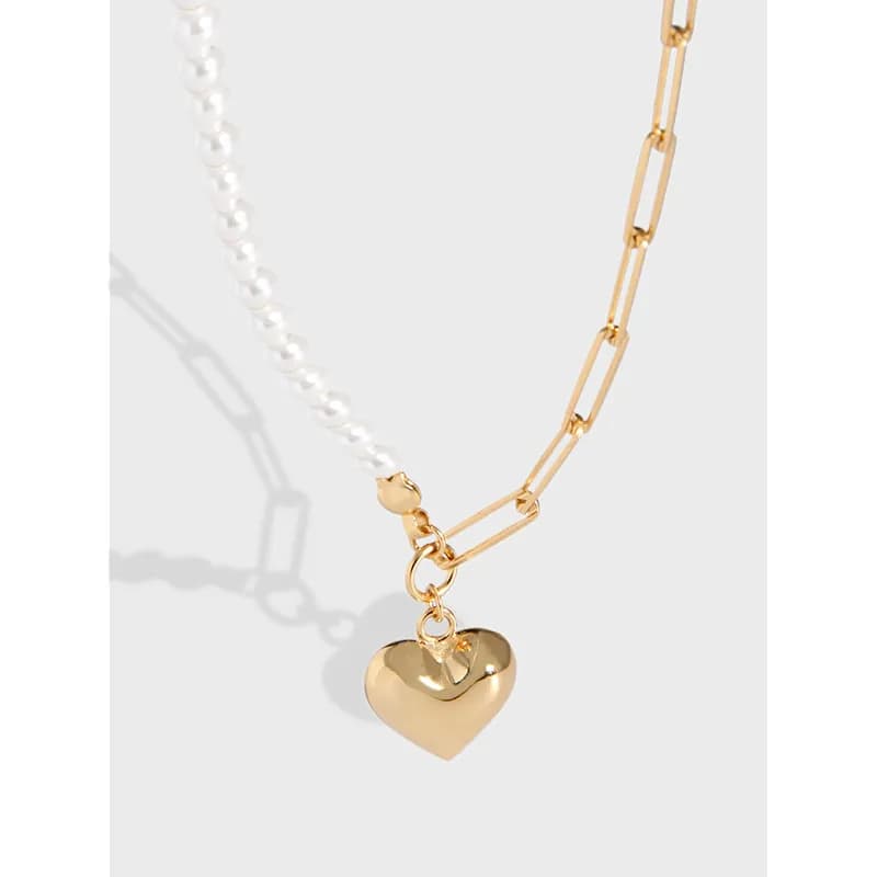 Close-up of a two-tone necklace with a gold heart pendant, featuring pearl beads on one side and a gold link chain on the other.