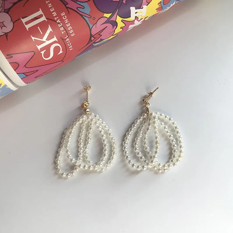 Two pearl bead teardrop earrings with polished sterling silver, hanging from gold-toned posts.