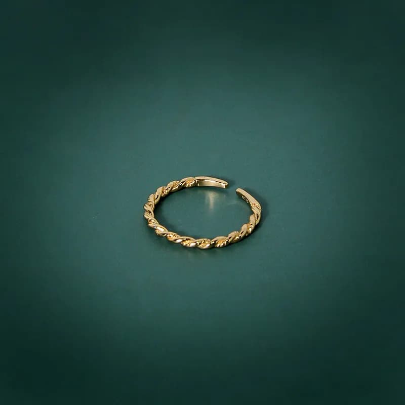 Open-ended sterling silver ring with twisted rope and leaf motifs on a teal background.