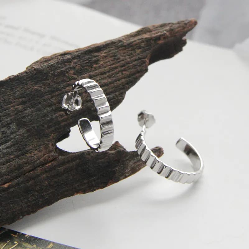 Sterling silver textured square hoop earrings displayed on a rustic piece of wood.