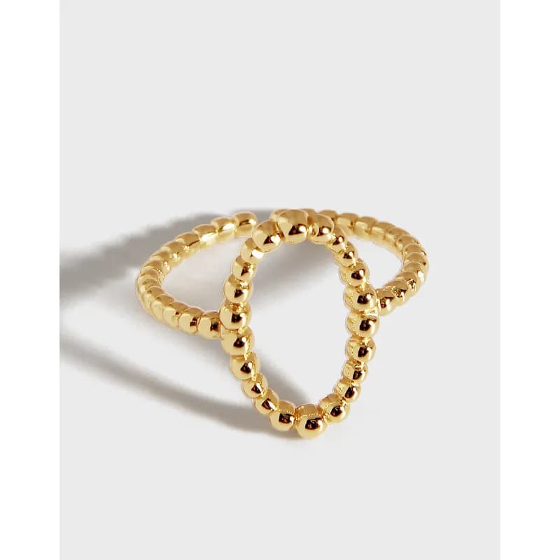 Two glossy gold-tone beaded rings interlocked on a white background.