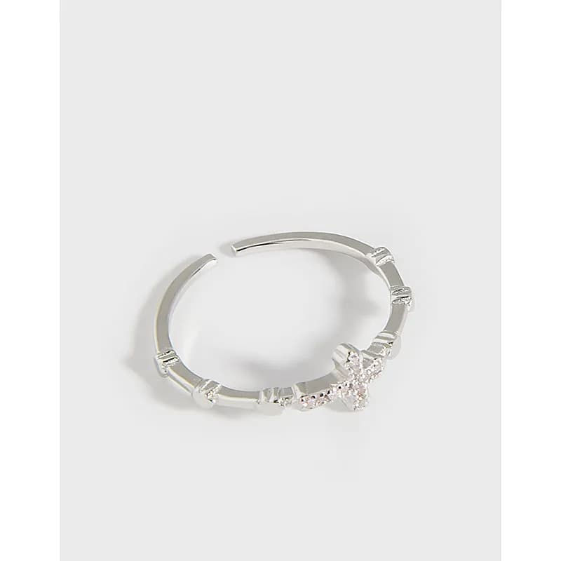 Polished sterling silver open ring with a small pavé floral cluster at one end.
