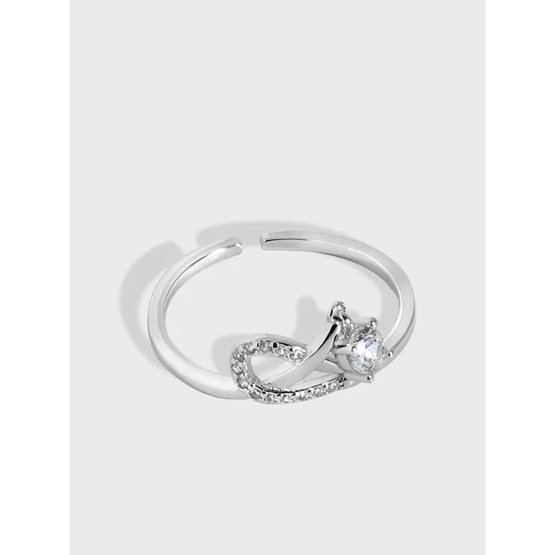 Polished sterling silver ring featuring an infinity-loop pavé curve and a solitaire stone.