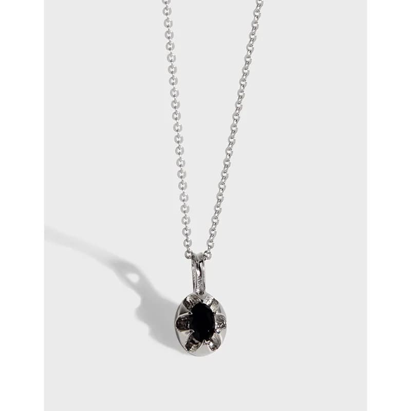 Polished sterling silver necklace with a circular pendant featuring a black center stone