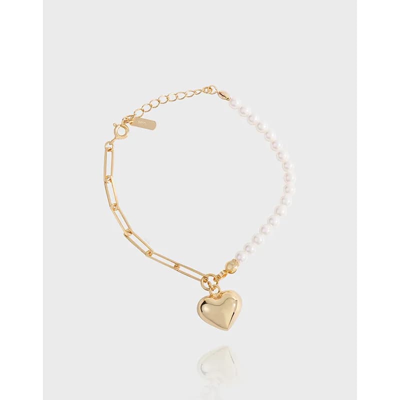 Polished two-tone bracelet with pearl strand on one side and gold chain on the other, featuring a heart charm.