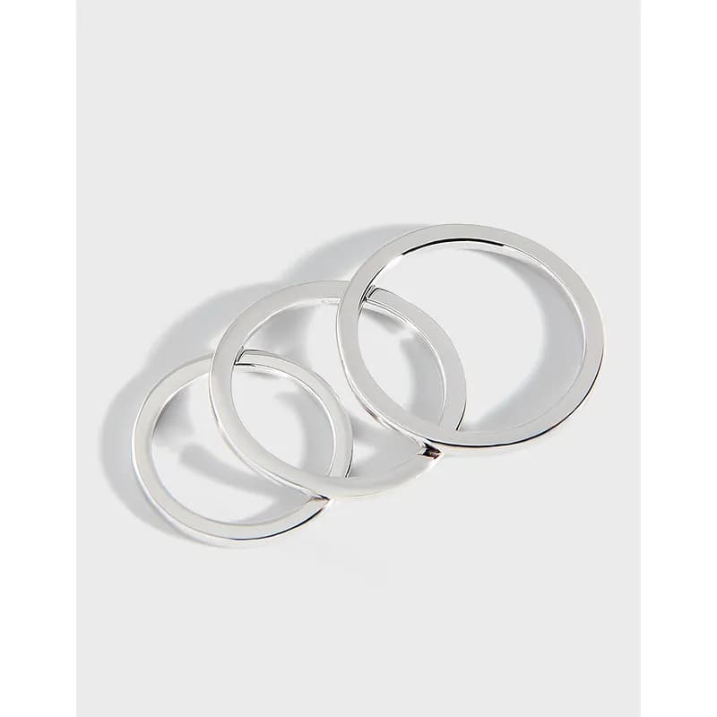Three polished sterling silver rings arranged in a loose interlocking trio.