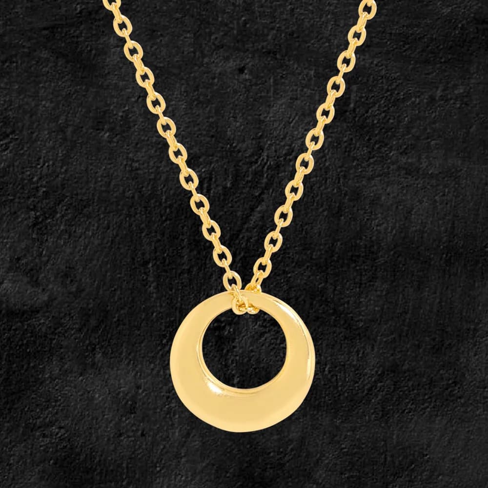 Polished circle pendant on a chain against a dark textured background