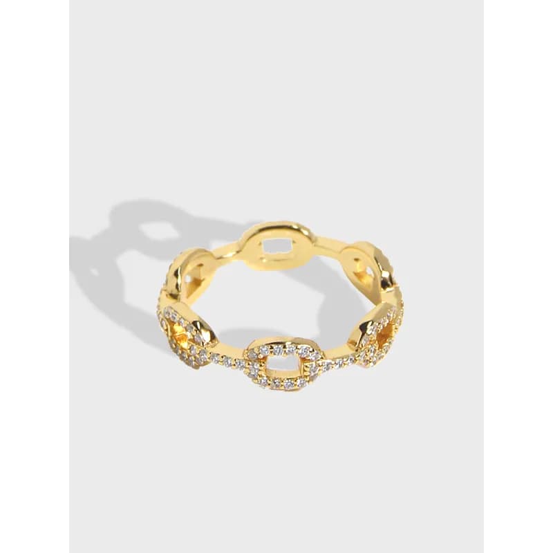 Gold-toned pavé link ring with crystals on a light gray background