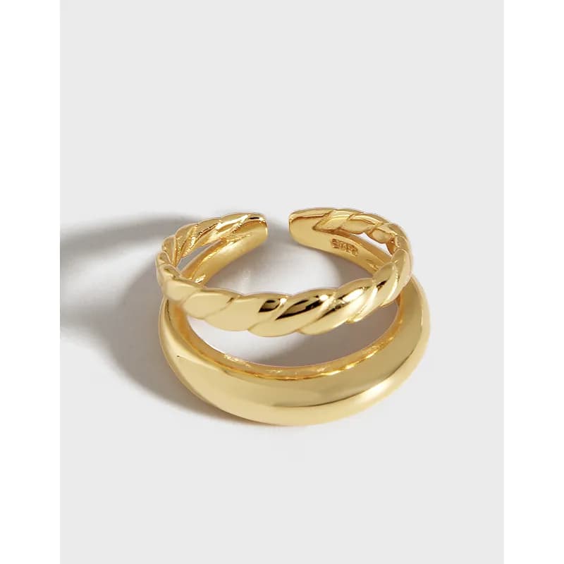 Two polished gold-tone rings, one smooth band and one twisted rope band, stacked together.