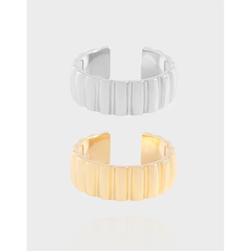 Open-cuff ribbed bar ring in silver and gold-tone finishes with a bold, structured texture.