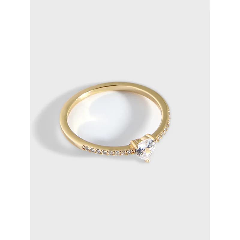 Polished sterling silver ring with a curved band, pavé stones along one edge, and a heart-cut center gemstone