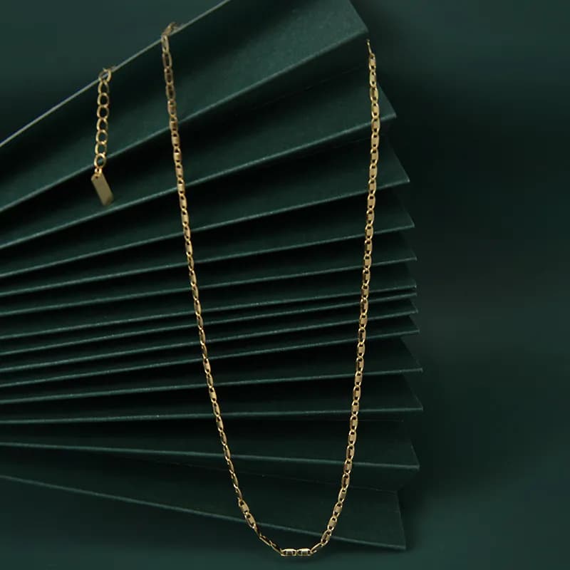 Polished sterling silver cable chain necklace displayed on a dark green backdrop.