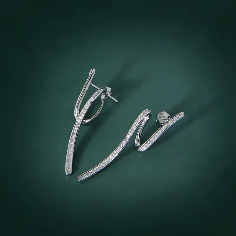 A pair of polished sterling silver curve earrings with pavé detailing on a dark green background.